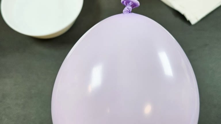 Einen Luftballon auf die gewünschte Größe der Schale aufpusten (unterer, breiterer Teil des Luftballons) und zuknoten.