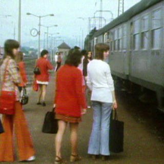 Mehrere junge Frauen am Bahnsteig, rechts ein dunkelgrauer Zugwaggon
