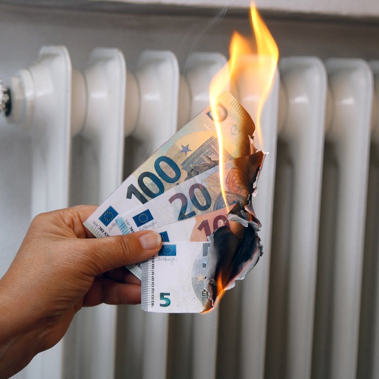 Brennende Geldscheine vor der Heizung - Geld und Energie sparen