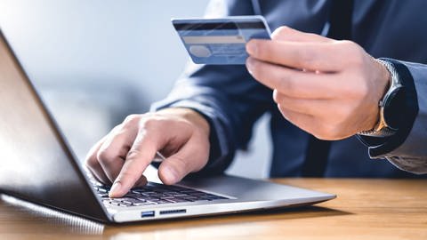 Mann mit Kreditkarte ins Laptop, um im Internet einzukaufen