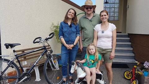 Familie Rothfuß mit Töchterchen steht mit Eva Röder vor ihrem Haus