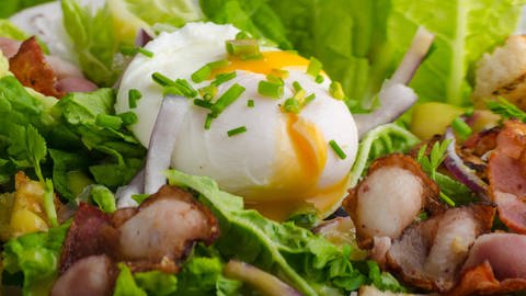 Ein pochiertes Ei auf einem bunten Salat